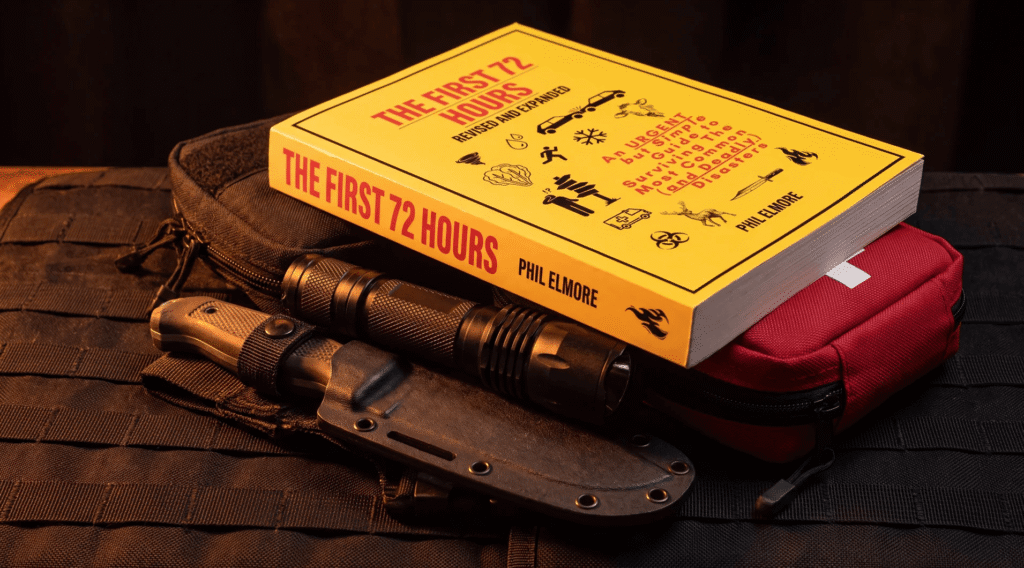 The First 72 Hours by Phil Elmore, revised and expanded edition, sitting on a tactical pack next to a fixed blade knife, a flashlight and a red medical pouch